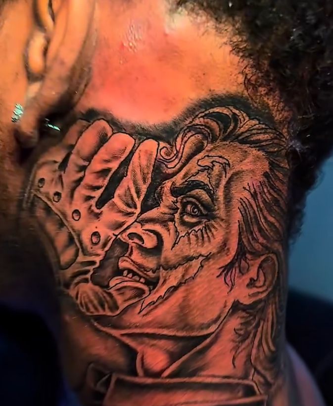 Black and grey neck tattoo of a clown face with a gloved hand and detailed shading.