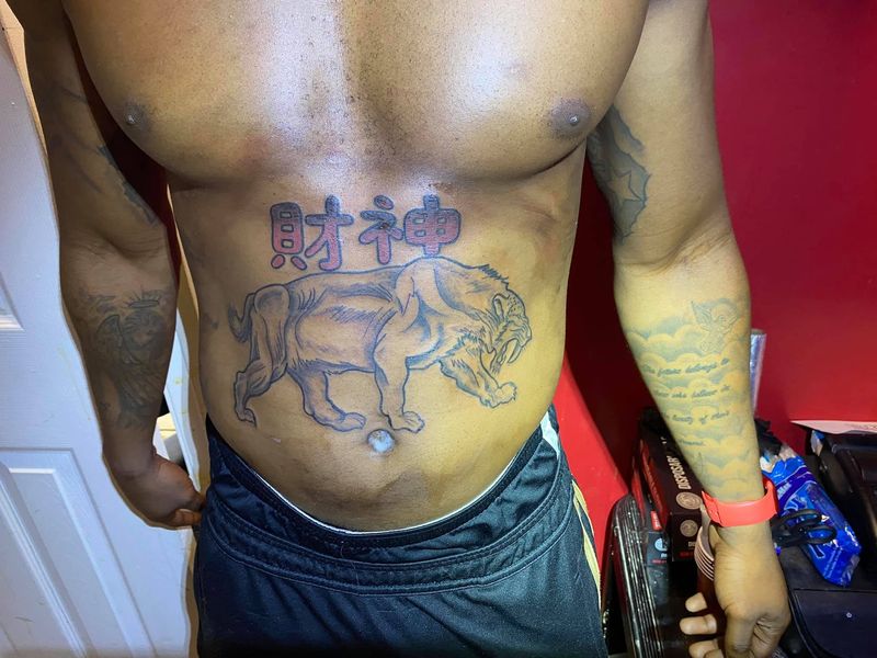 Stomach tattoo of a walking elephant beneath two Chinese characters.