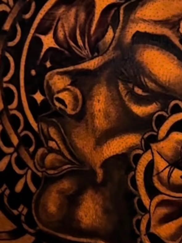Close-up of a black and grey portrait tattoo of a woman's face with an ornamental pattern behind her.